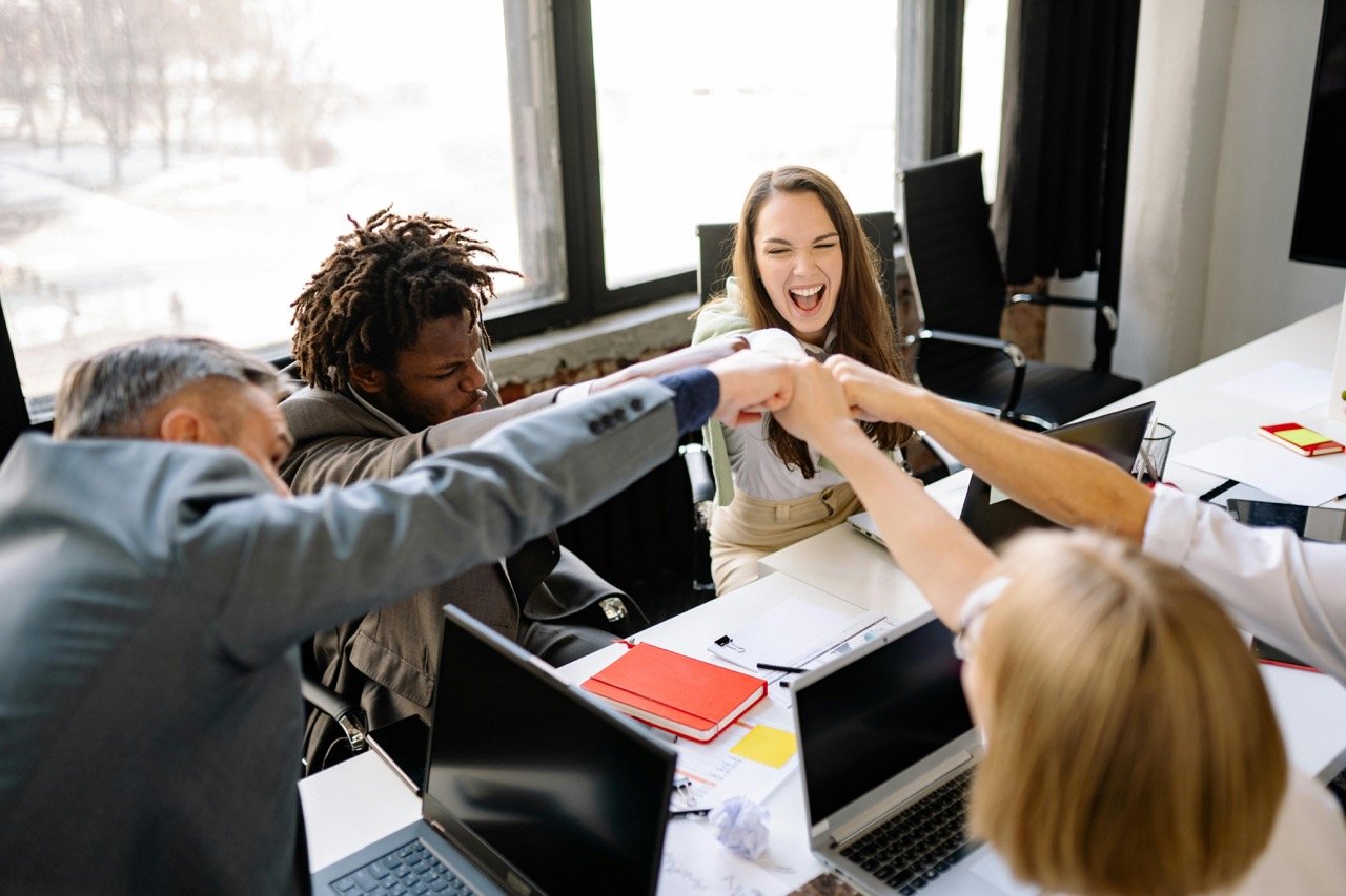 Group of professionals celebrating around a meeting table in modern office.