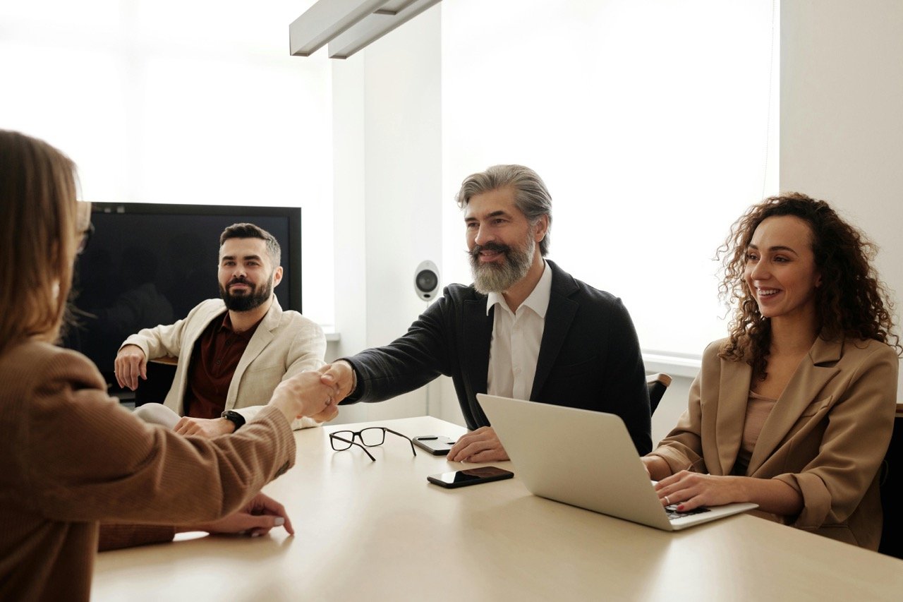 Business professionals in modern meeting room shaking hands.