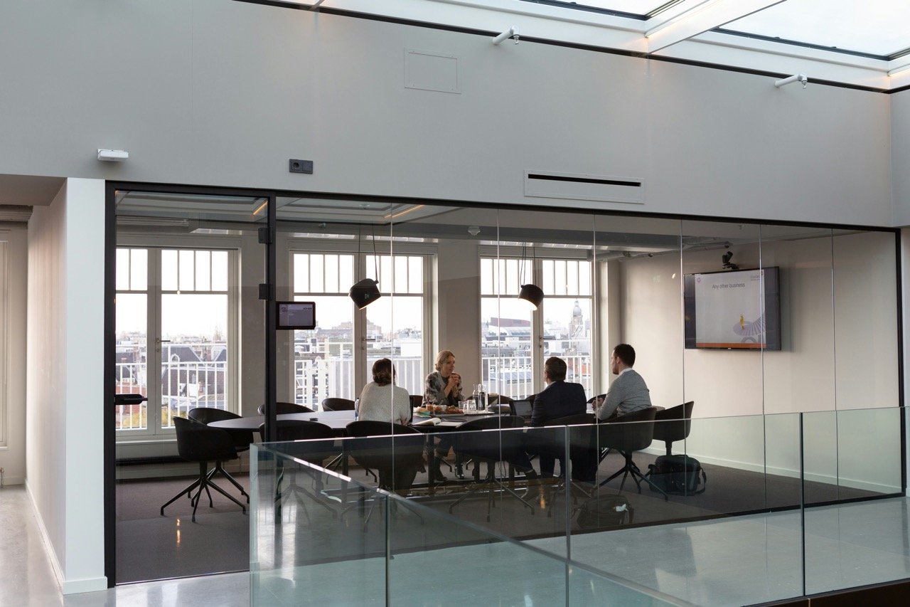 Business professionals in meeting room with glass walls.