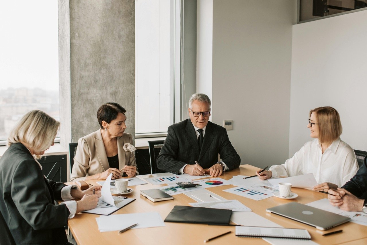 Four business professionals meeting in a modern office conference room about coaching and development.