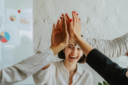 Image of happy professionals giving each other high-fives for a successful coaching culture.
