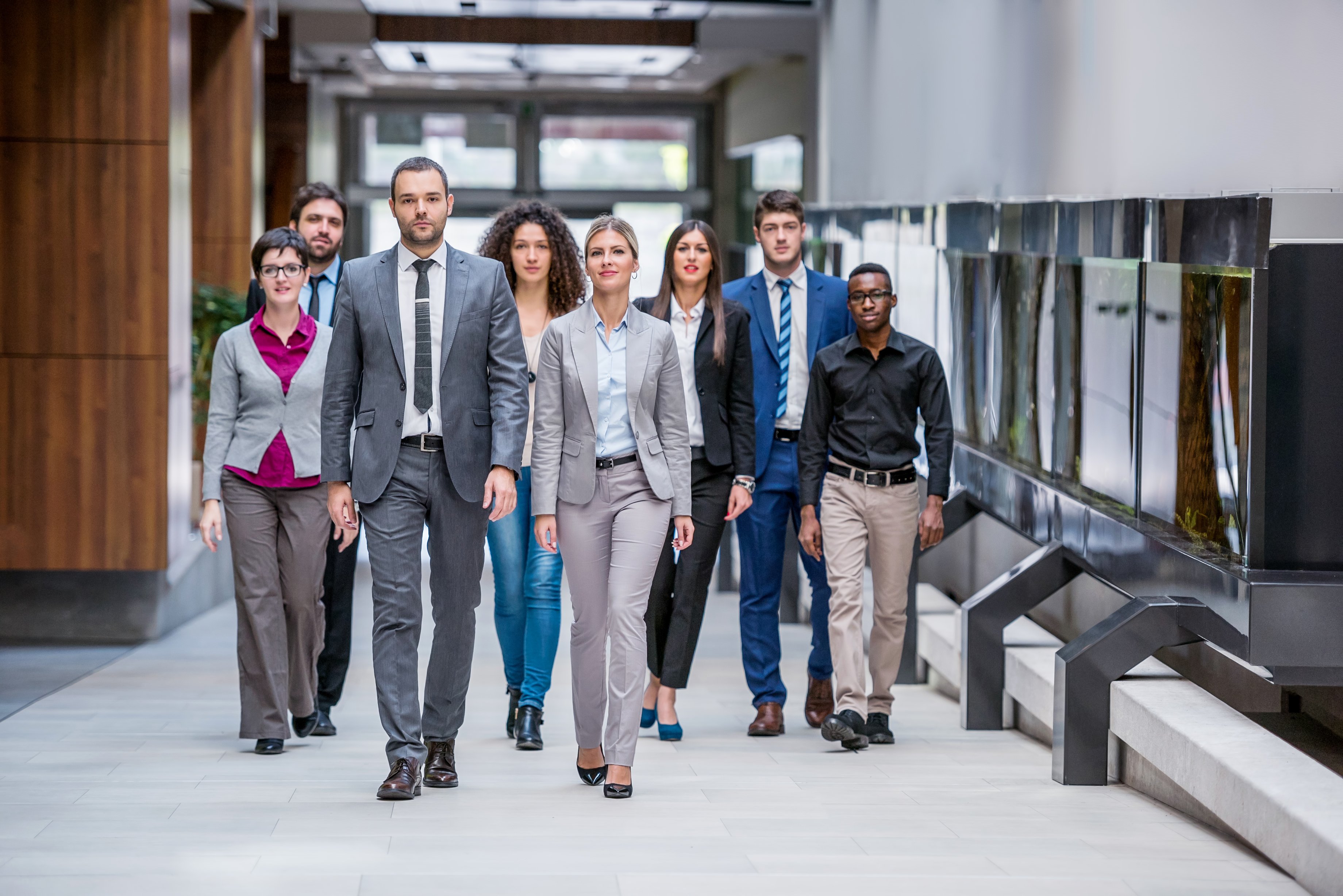 Group of business professionals walking through modern office space.